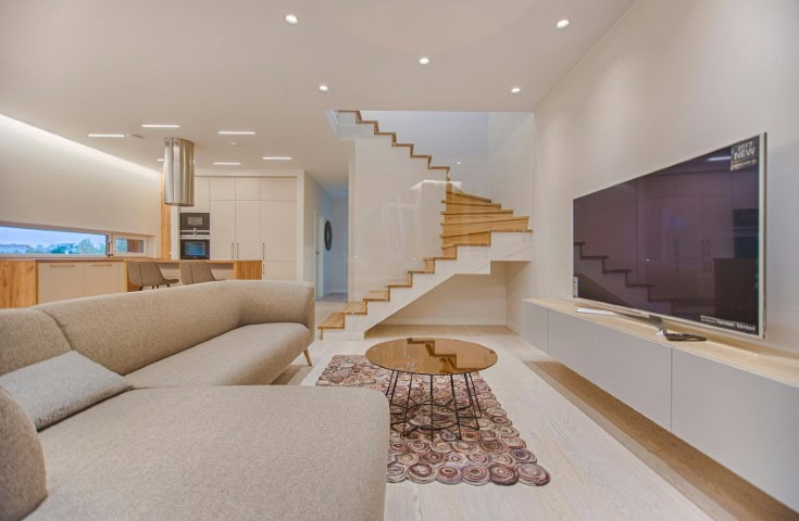 Modern luxury family room with plush seating, a fireplace, and large windows offering natural light